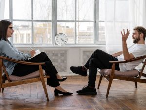 A therapist engaging in a counseling session with a male patient to support mental health.